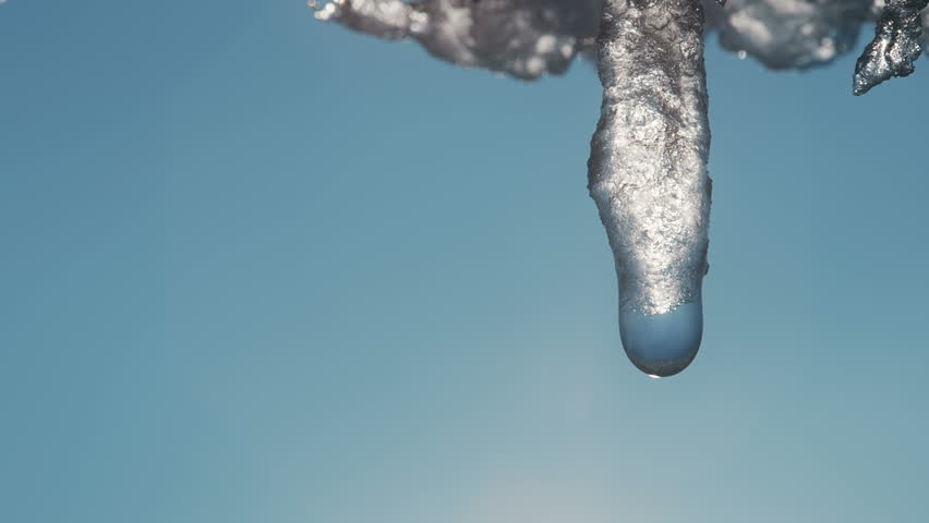 Beautiful dripping icicles on a warm bright sunny day. Melting icicle on a blue background, seamless loop. Endless loop, loopable Royalty-Free Stock Footage #1017368113