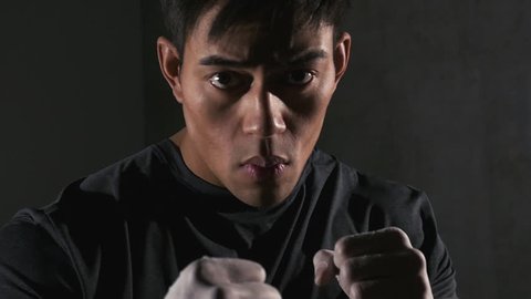Asian boxer throwing punches at camera. Close up.