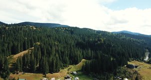 Aerial drone footage of little highland town in Carpathian mountains surrounded with green hills & forest.Beautiful landscape video shot with flying camera in bright autumn morning.Travel destination