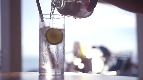 Pour refreshing sparkling water from a bottle into a glass with ice and a slice of lime. HD, 1920x1080, slow motion