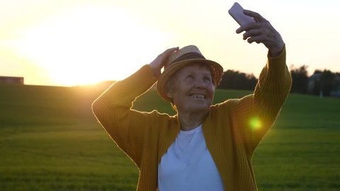Hip Grandma Taking Selfie In Straw Hat With Smartphone At Sunset