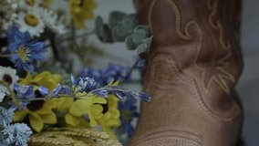 Cowboy boots of a Bride and Groom standing side by side next to flowers.