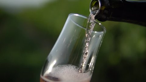 champagne pouring into the glass in vineyard