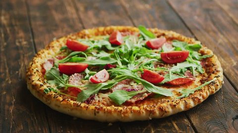 Side view of delicious italian pizza served on dark brown wooden table with copy space