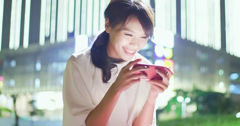 woman play mobile game happily with shopping mall at night