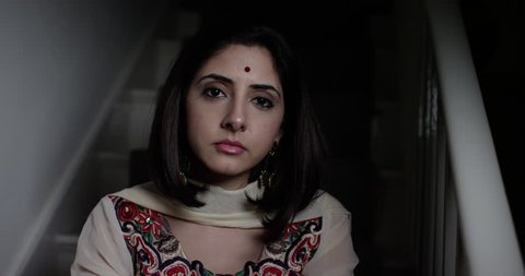 4K Depressed South Asian woman sitting alone on staircase, staring at camera. Slow motion.