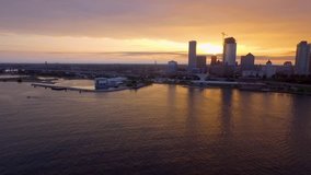 This stunning slow motion aerial drone clip flies over the serene harbor of Milwaukee Wisconsin at sunset with the sky seemingly on fire with an orange glow. A perfect establishing shot.