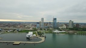 An aerial drone clip shows off the harbor and lakefront skyline of Milwaukee, Wisconsin, as a storm moves over the city. This moody piece is somber with the dark clouds hanging over the city.