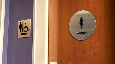 Women's bathroom sign on wooden door in corporate office environment.