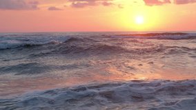 Sunset on sea beach with waves and colorful orange sky. 4k video footage. Travel concept 