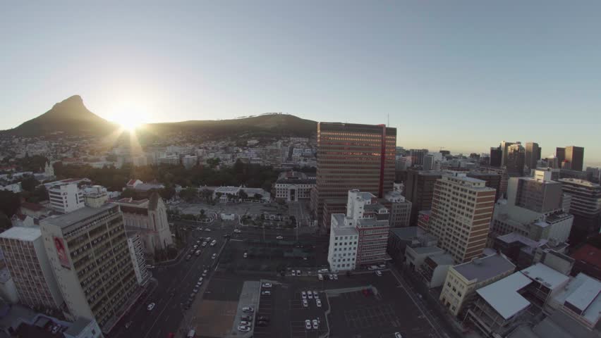 Beautiful sunset above the city of cape town, south africa. This is a super wide shot, filmed from a roof top. The sun goes down next to the famous lions head with the skyline in the front.