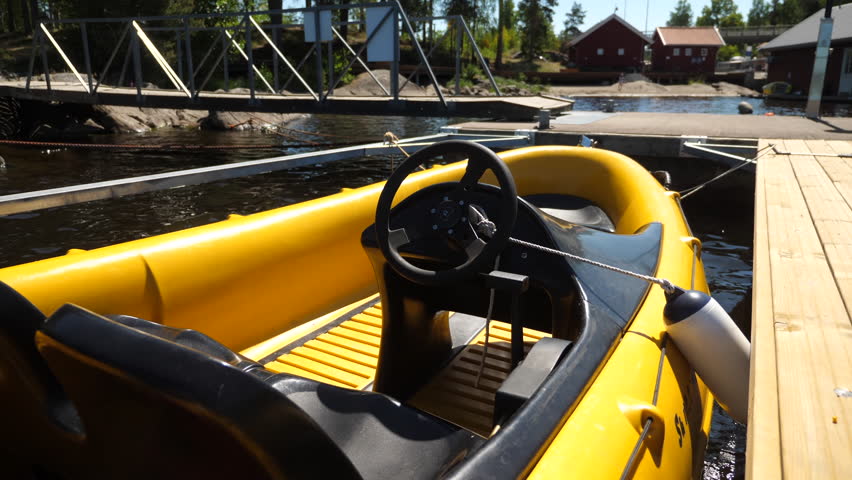 A small yellow powerboat tied to the pier on a lake from behind, MEDIUM SHOT.