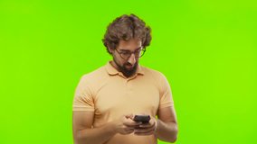 young bearded silly man with an smart telephone against chroma key editable background. ready to cut out the person.