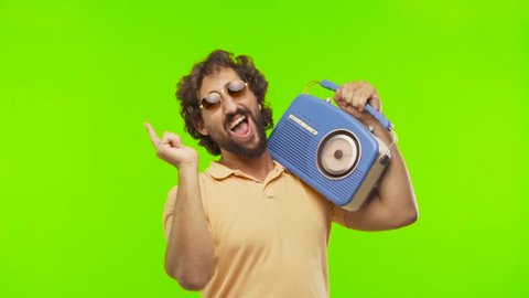 young bearded silly man dancing with a vintage radio against chroma key editable background. ready to cut out the person.
