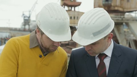 Close-up of the meeting of two engineers in protective helmets in the seaport