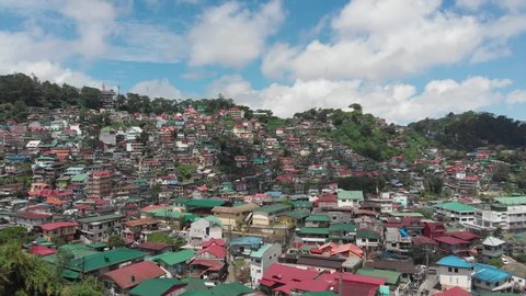 An overlooking drone shot of Baguio City, with a lot of houses on a Mountainous Region.