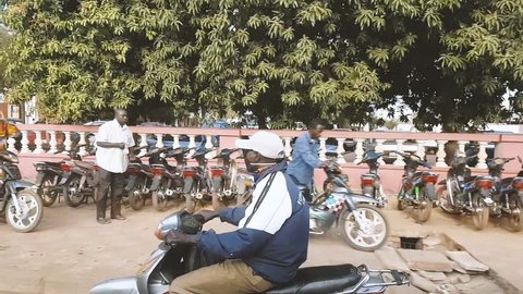 BAMAKO, MALI - CIRCA 2017: View from the humanitarian mission transportation vehicle of the poor street of the Bamako, people commuting on motorcycles in front of Hotel de Ville city hall