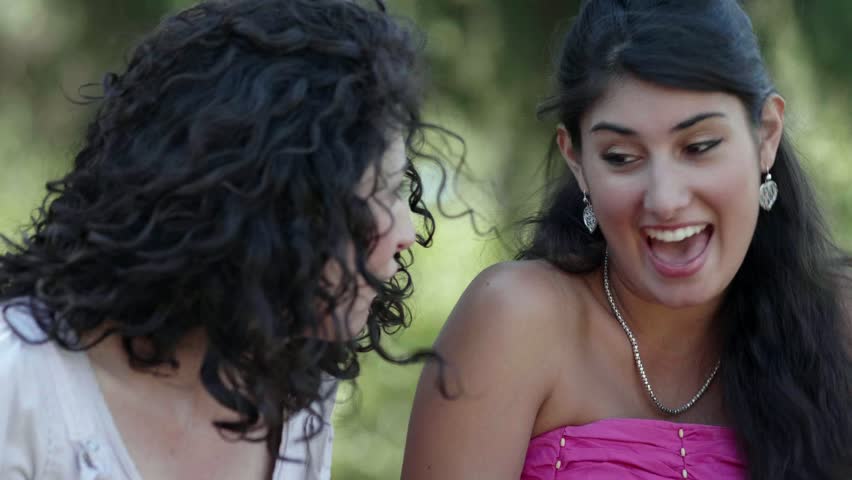 Happy pretty young women laughing,chatting using tablet in the park