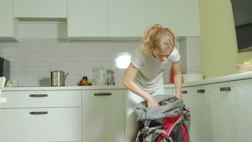 A woman tourist collects things in a backpack in the kitchen of the house and prepares for a trip 4k