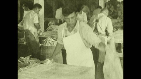 1930s: Men prepare cod and halibut in warehouse. Man fillets halibut and removes skin.