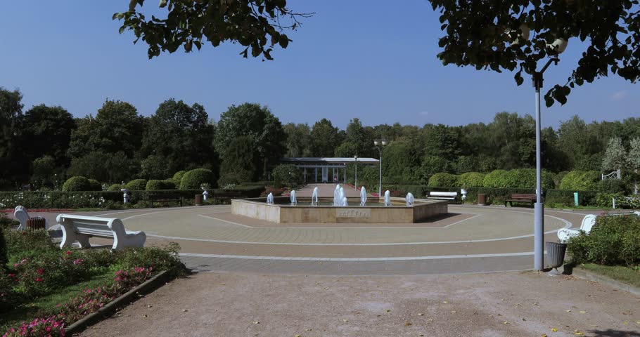 In a beautiful dress the girl on the edge of the fountain plays with a stream of water. Papa supports her