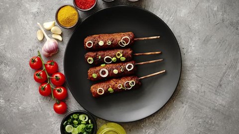 Barbecued turkey kebab decorated with fresh onion and chive black plate, top view. Dark stone background.