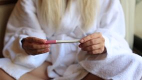 Female hands holding pregnancy test, turning to show two lines, family planning