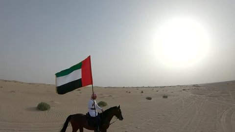 Man riding horse and holding UAE flag in desert 