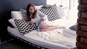 Young, cute woman watching film on tablet on bed 
