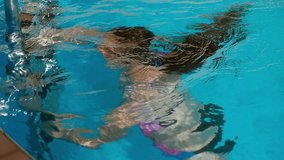 Cute teenager girl swimming underwater in the pool, slow motion video