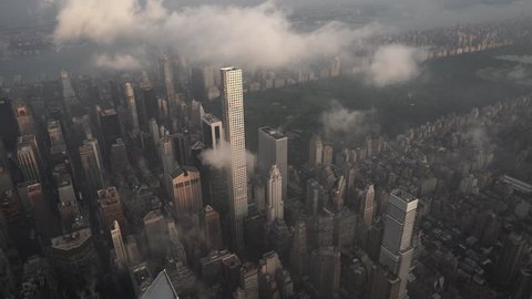 New York City Circa-2015, aerial view flying over Midtown Manhattan skyscrapers toward Central Park at sunrise, with fog and low level clouds at sunrise
