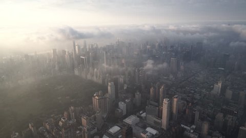 New York City Circa-2015, aerial view of Manhattan at sunrise, flying from the Upper West Side and Central Park to Midtown covered in fog and low level clouds
