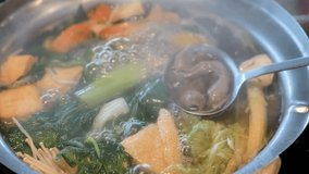 Suki or Shabu boiling in electric pot with turnips, morning glory, pork chops, squid, corn, vermicelli and pork. video Slow motion
