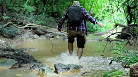 Adventurers Asian men.  walking through small stream river in the forest. Adventures and extreme tourism, overcoming obstacles. Travel Lifestyle and success concept. Video Slow motion