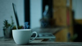 Coffee cup smoke on wood table and laptop background. Video Slow Motion