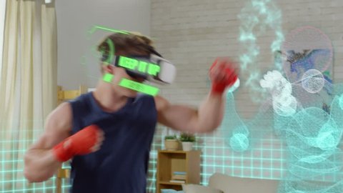 Young muscular man in VR headset with projected physical activity metrics boxing with holographic opponent while training in the living room