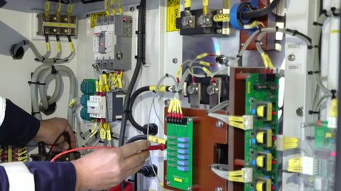 electrical circuit / technician examining fusebox with multimeter probe

