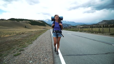 young tourist woman with a backpack hitchhiking on a mountain road 50 fps