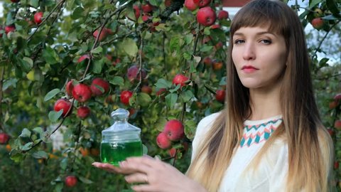 Liquid soap, a girl demonstrates shampoo on the background of an apple tree with apples.