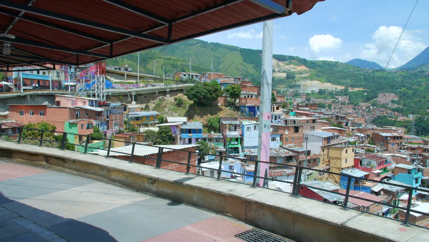 Girl walks on walkway under roof with view of Comuna 13 neighborhood, Medellin Colombia