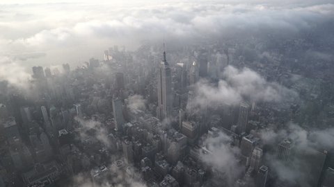 New York City Circa-2015, aerial view flying over Midtown Manhattan, featuring the Empire State Building, with low level clouds at sunrise
