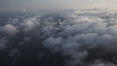 New York City, New York - Circa 2015: Aerial view of Manhattan in the morning from the Financial District, with One World Trade Center peeking above a layer of low level clouds, extending beyond the horizon