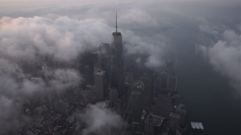 New York City, New York - Circa 2015: Aerial view orbiting One World Trade Center and Lower Manhattan Financial District skyscrapers from the Hudson River, covered by fog and low level clouds at sunrise