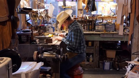 FORT WORTH, TEXAS / USA - JULY 2018: Man working as artisan in souvenir shop and painting leather belt. American cowboy at work in traditional Western store in Fort Worth, Texas, United States