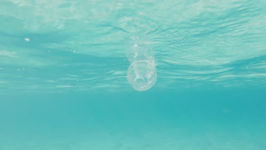 Underwater Slow Motion Shot Of A Clear Plastic Bottle Floating On The Surface Polluting The Turquoise Clear Ocean. Royalty-Free Stock Footage #1017556519
