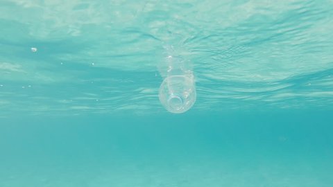 Underwater Slow Motion Shot Of A Clear Plastic Bottle Floating On The Surface Polluting The Turquoise Clear Ocean.