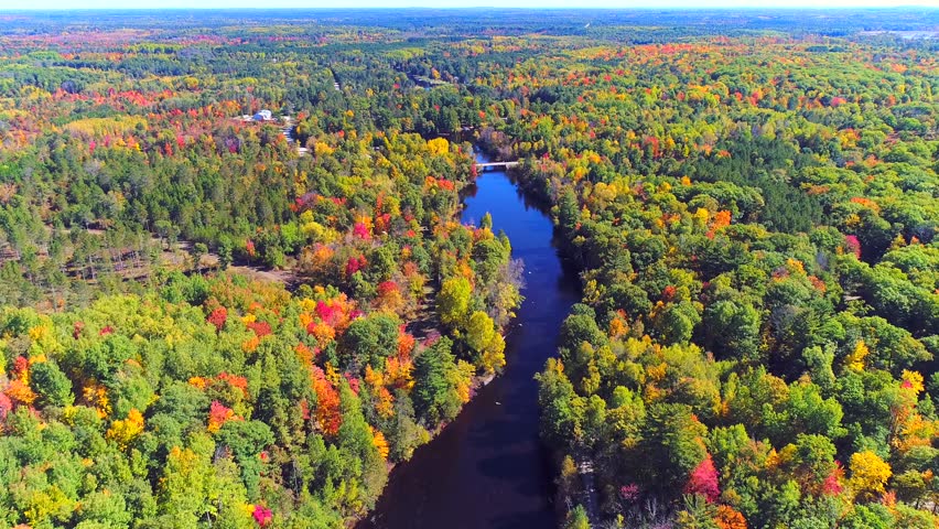 Autumn in Northern Wisconsin, colorful scenic treetop drone flyover of amazing forests and river.