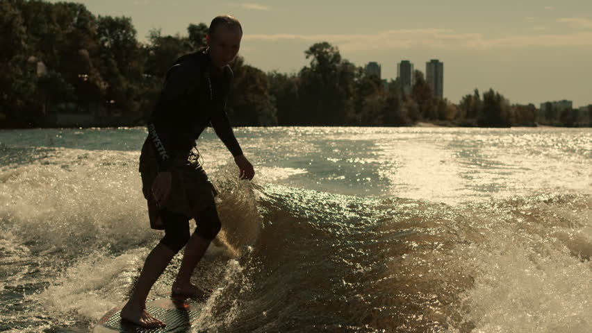 Wake surfer enjoy evening waves. Close up of rider surfing waves at sunset. Man surfing on wavws at sunset