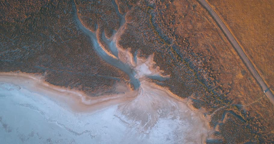 Aerial over desert road, grass and rolling hills of Carrizo Plain Monument at sunrise. The San Andreas fault runs through the park.