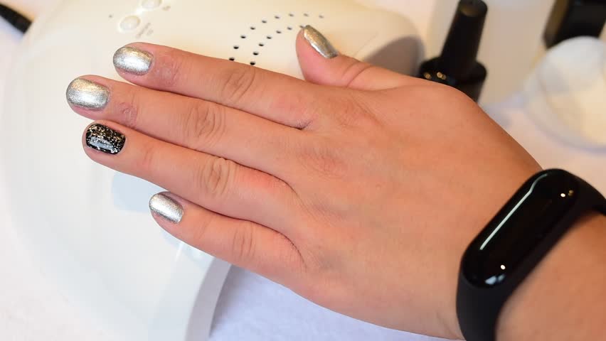 Womans hands close up painting dye nails manicure uv led lamp nail polish smart watch